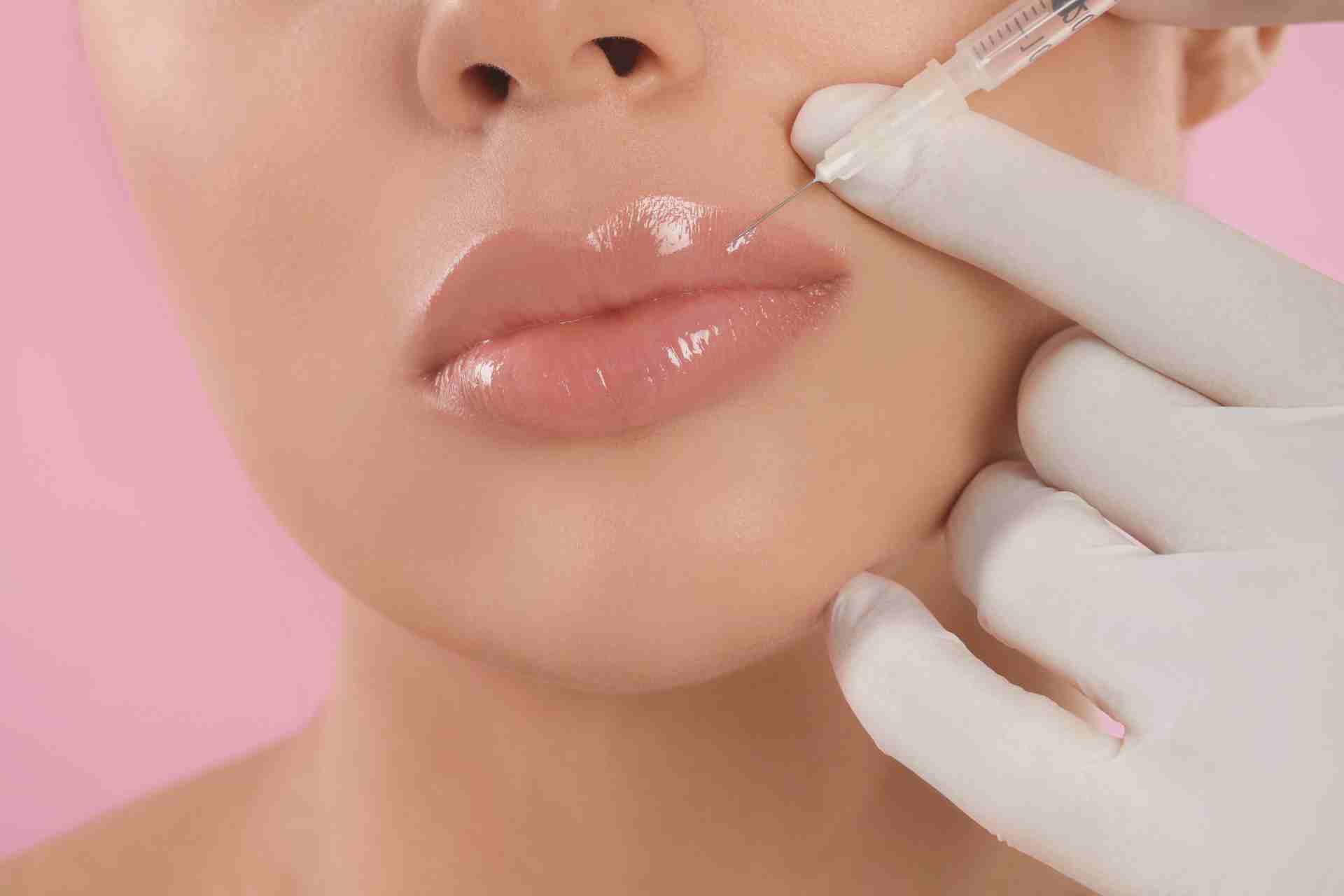 Young Woman Getting Lips Injection on Pink Background.
